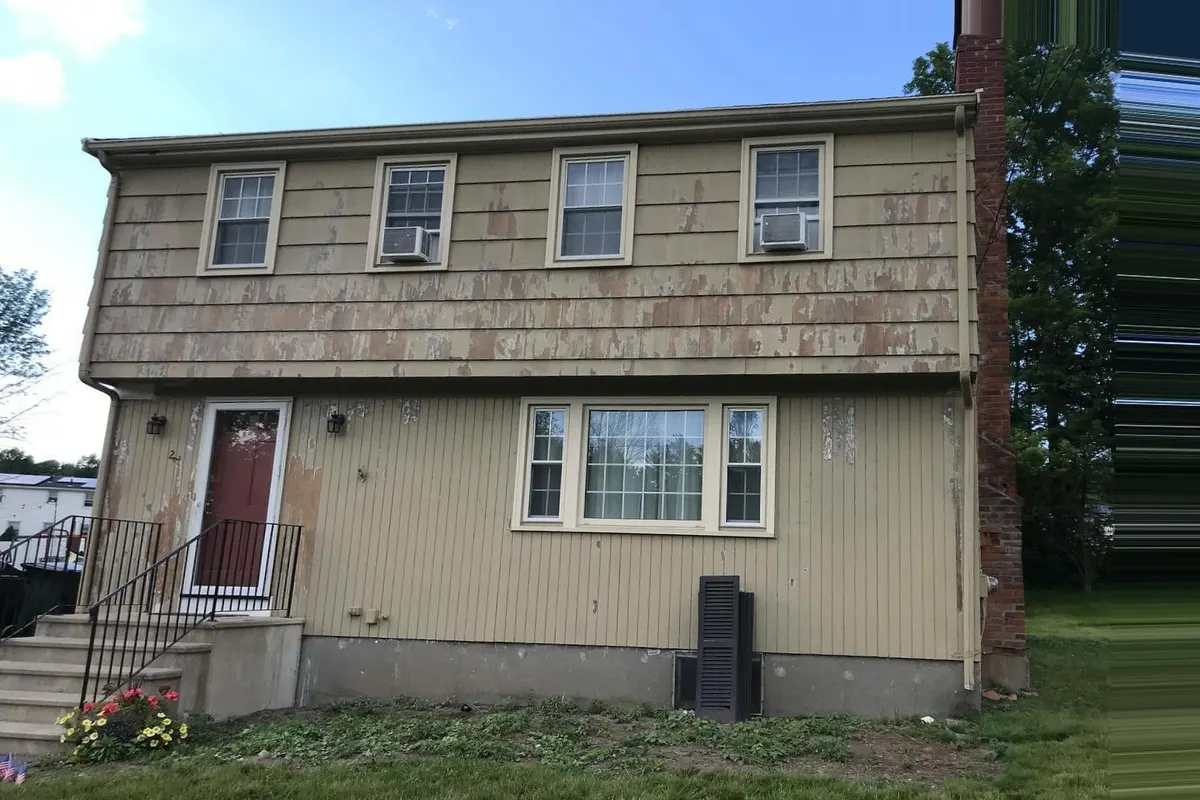 The same house before: faded tan siding with peeling paint