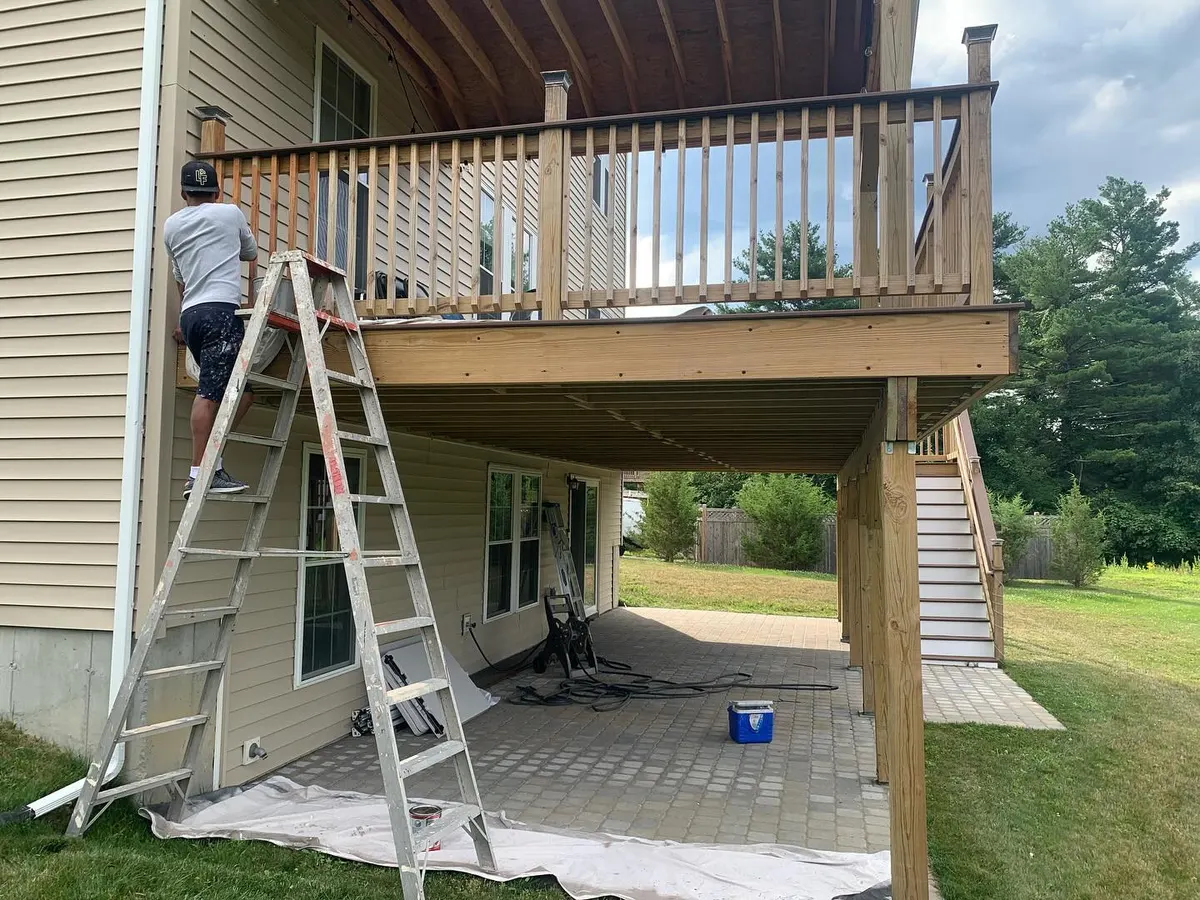 De Sousa painter working on a deck from a ladder