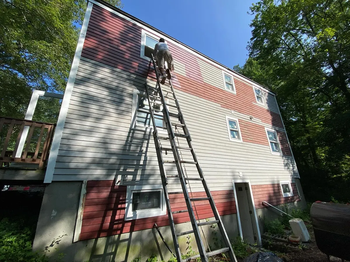 Painter on a ladder giving a house a new siding color in Westborough